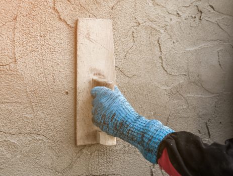 plasterer concrete worker at wall of house construction