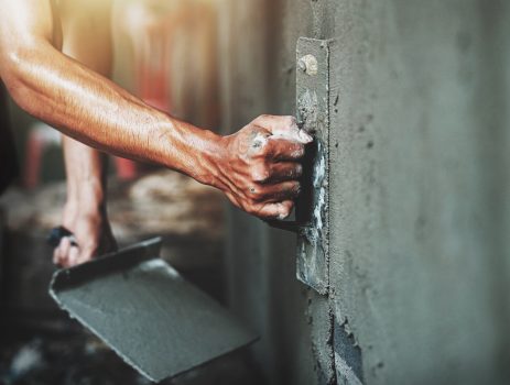 closeup hand of worker plastering cement at wall for building house